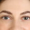 Close-up of woman applying what is Latisse eyelash growth treatment along upper lash line