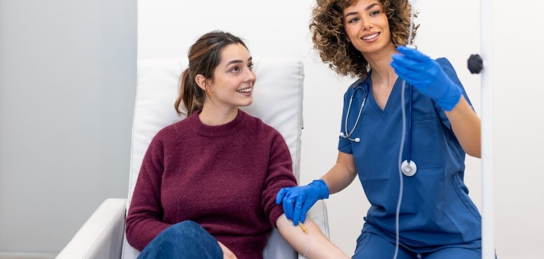 Provider administering IV hydration effects treatment to a smiling patient at a wellness clinic