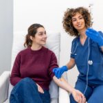 Provider administering IV hydration effects treatment to a smiling patient at a wellness clinic